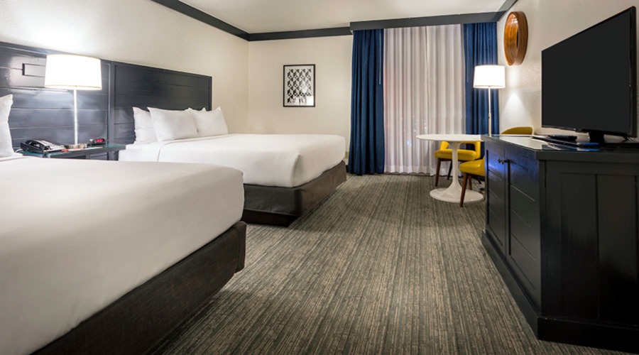 Two queen bed next to window with airport view.
